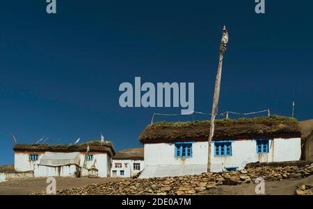 Dorfhäuser mit Strohdächern und Trockenfutter mit buddhistischen Gebetsfahnen und Trockenmauern in Hikkim, Himachal Pradesh, Indien. Stockfoto