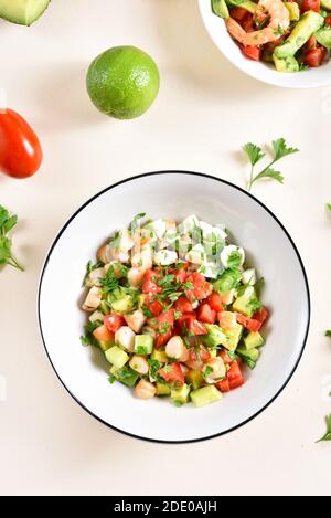 Avocado, Garnelen, Tomate und Mozarella Salat mit Gemüse in Schüssel auf hellem Stein Hintergrund. Gesunde Ernährung Ernährung Konzept. Draufsicht, flach liegend Stockfoto