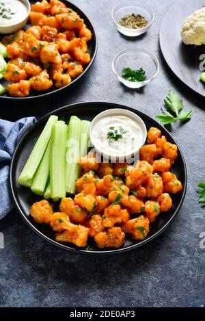 Blumenkohlbüffelflügel mit Sellerie und Sauce auf Teller über blauem Stein Hintergrund. Gesunde Ernährung, pflanzliche Ernährung Konzept. Stockfoto