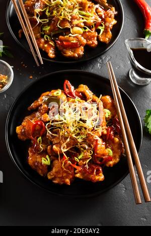 Würziger Knoblauch gebratenes Huhn (Kkanpunggi). Asiatisches Huhn in süßer und saurer Sauce auf Teller über schwarzem Stein Hintergrund Stockfoto