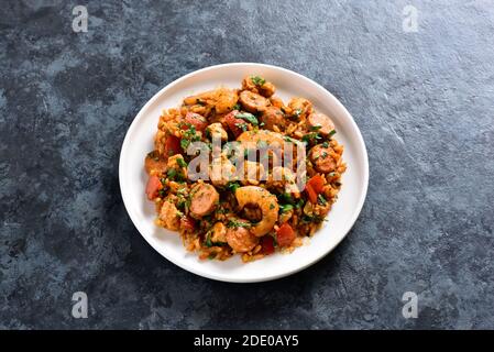 Kreolische Jambalaya mit geräucherter Wurst, Hühnerfleisch und Gemüse auf Teller über blauem Stein Hintergrund mit Kopierraum. Nahaufnahme Stockfoto