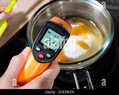 Kochen süßer Biskuitkuchen zu Hause - Messung der Temperatur von Zutaten in  Glasschale auf Wasserbad mit Infrarot-Thermometer Auf Herd in der heimischen  Küche Stockfotografie - Alamy