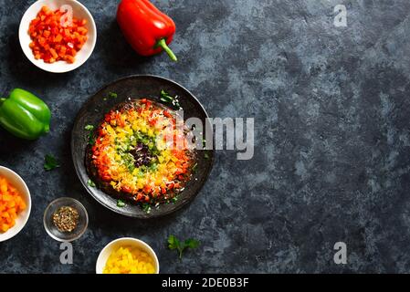 Regenbogen Veggie Paprika Pizza Kruste auf blauem Stein Hintergrund mit freiem Text Raum. Vegetarisch vegan oder gesundes Essen Konzept. Draufsicht, flaches Lay Stockfoto