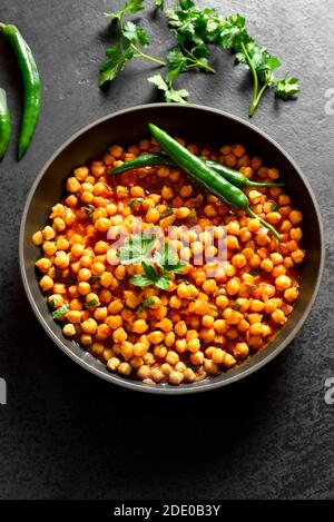 Knusprig geröstete Kichererbsen. Gericht im indischen Stil über schwarzem Stein Hintergrund. Vegetarisches veganes Food Konzept. Stockfoto