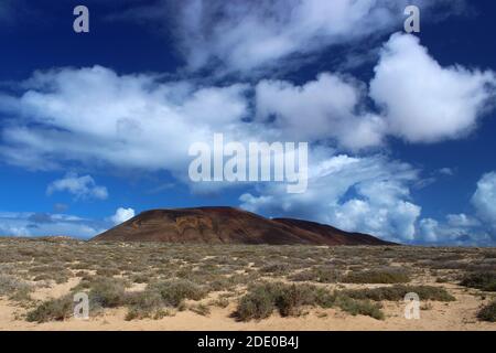 Panoramablick auf den Vulkan Agujas Grandes unter einem blauen Himmel mit weißen Wolken. La Graciosa, Lanzarote, Kanarische Inseln, Spanien. Stockfoto