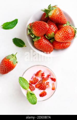 Erdbeerjoghurt mit frischen Beeren auf hellem Stein Hintergrund. Gesundes Essen und Trinken Konzept. Draufsicht, flach liegend, Nahaufnahme Stockfoto