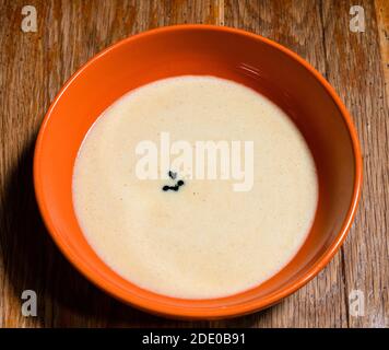 Kochen süßen Biskuitkuchen zu Hause - Draufsicht auf Flüssiger Teig mit Tropfen grüner Lebensmittelfarbe in Orange Schüssel auf alten Holztisch in der heimischen Küche Stockfoto