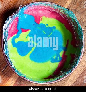 Kochen süßen Biskuitkuchen zu Hause - Draufsicht auf Bunte Mischung aus rohem Teig in Springform auf alt Holztisch in der heimischen Küche Stockfoto