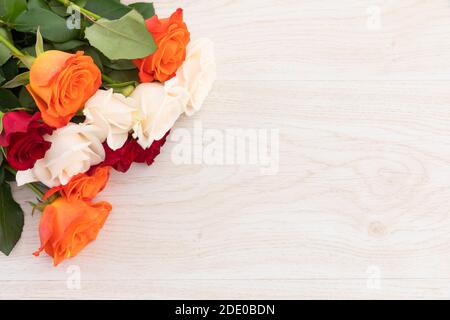 Strauß orangefarbener, weißer und roter Rosen auf Holzgrund Stockfoto