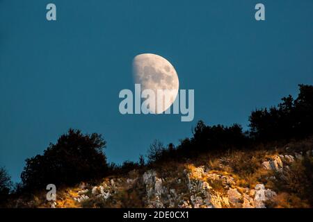 Klippen über dem Ardeche Fluss sind mit dem Licht der untergehenden Sonne durchstreiften, während der Mond über ihnen aufgeht. Stockfoto