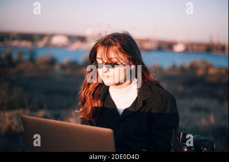 Mädchen in lustigen Brillen funktioniert auf Laptop Stockfoto