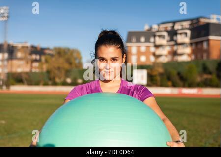 Junge Frau macht Übung mit einem Fitball auf dem Gras Stockfoto