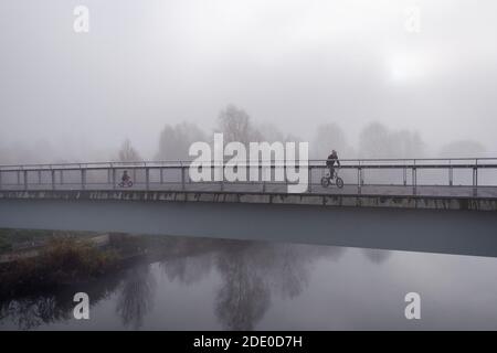 Radfahrer auf Brücke im Queen Elizabeth Olympic Park mit Nebel und Nebel. November 2020 London, England, Vereinigtes Königreich, Europa Stockfoto