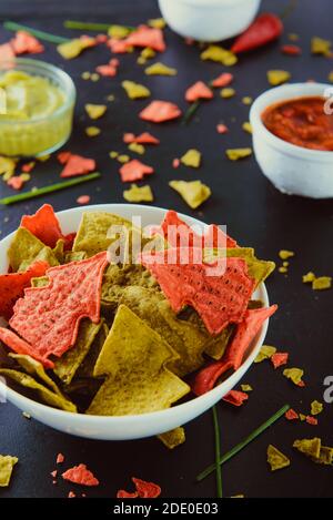 Corn Green und Red Tortilla Chips in Form eines Weihnachtsbaums in weißer Schüssel mit Salsa, Guacamole, Käse, saure Sahne Dipping Saucen auf die Stockfoto