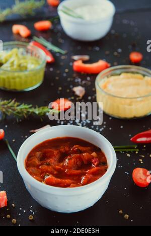 Close up Schüssel mit Salsa Sause mit Mayo-Sauerrahm, Guacamole, Käse Dipping Saucen mit Zutaten und Gewürzen auf dem schwarzen Hintergrund. Dressing Stockfoto