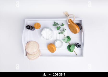 Bambus-Gesichtsbürste, Loofah Pads, kosmetische Naturöl Serum, handgemachte Cremes und Eukalyptus auf Holz Tablett DIY Home umweltfreundliche Spa, Massage, Peeling Stockfoto