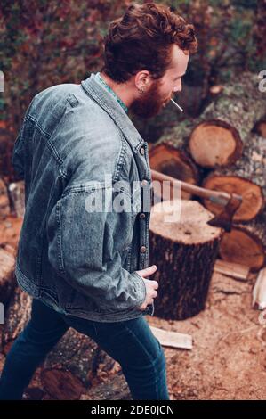Brutal Rotschopf Kerl mit Zigarette wird bereit, Holz zu hacken Stockfoto