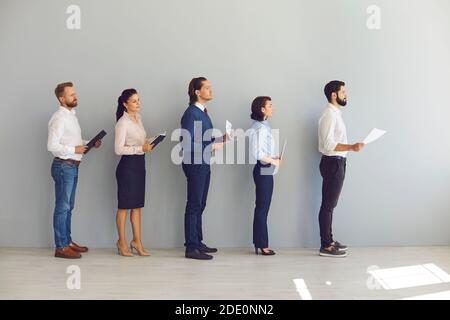 Junge Kandidaten für freie Stelle oder Arbeitssuchende stehen in der Schlange Mit Lebensläufen und Warten auf Interview Stockfoto