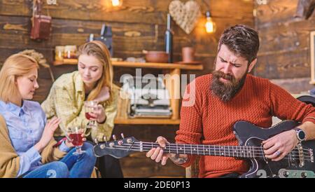 Mann mit langen buschigen Bart singen leidenschaftlich, Musikkonzept. Mädchen trinken Tee oder Wein und genießen schöne Melodien. Bärtiger Mann spielt Gitarre. Gitarrist mit Hipster Bart, der neuen Song aufführt. Stockfoto