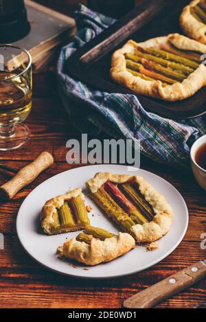 Rhabarber Mini Galette in Scheiben geschnitten auf weißem Teller mit Glas Weißwein Stockfoto