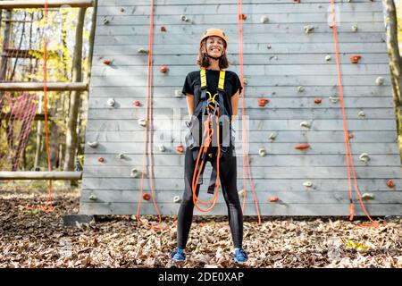 Porträt einer gut ausgerüsteten jungen Frau, die davor steht Der Kletterwand im Vergnügungspark Stockfoto