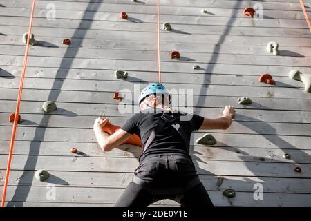 Gut ausgerüsteter Mann klettert die Wand im Freien im Park für Sportunterhaltung Stockfoto