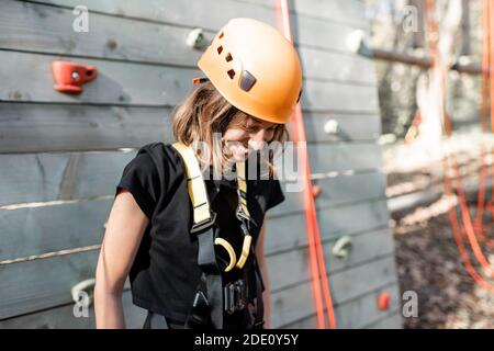 Porträt einer glücklichen jungen Frau in Sportausrüstung in der Nähe Die Kletterwand im Park für sportliche Unterhaltung Stockfoto