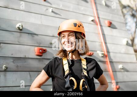 Porträt einer glücklichen jungen Frau in Sportausrüstung in der Nähe Die Kletterwand im Park für sportliche Unterhaltung Stockfoto