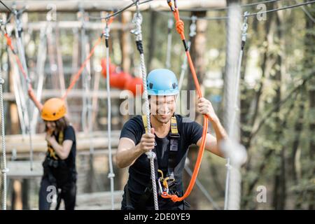 Gut ausgestattete Mann und Frau mit einer aktiven Erholung, Klettern Seile im Park mit Hindernissen im Freien Stockfoto