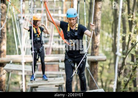 Gut ausgestattete Mann und Frau mit einer aktiven Erholung, Klettern Seile im Park mit Hindernissen im Freien Stockfoto