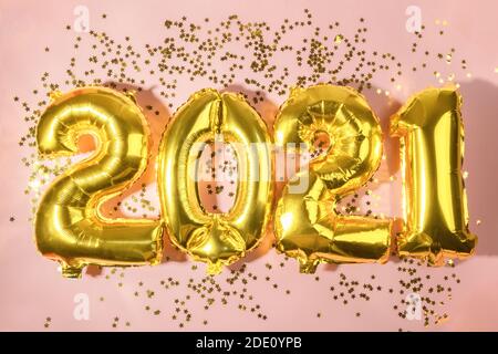 Frohes Neues Jahr 2021. Urlaub goldene Folie metallic Ballon Zahlen 2021 und Sterne Konfetti auf rosa Hintergrund. Obere horizontale Ansicht Neujahr und Urlaub Stockfoto