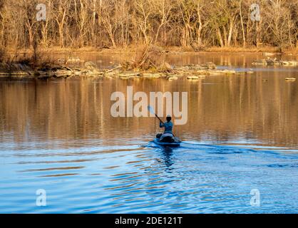 Great Falls, Virginia, USA - 26. November 2020. Eine Frau rudert mit dem Kajak zum sonnenbeschienenen fernen Ufer des Potomac. Stockfoto