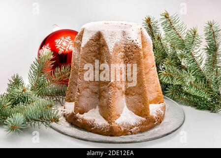 Pandoro, traditionelle italienische Weihnachtskuchen, mit Puderzucker zwischen Tannenzweigen und Weihnachtskugel, isoliert auf Weiß Stockfoto