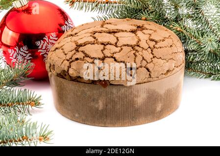 Panettone, traditionelle italienische Weihnachtskuchen zwischen Tannenzweigen und roter Weihnachtskugel, isoliert auf Weiß Stockfoto