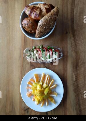 Gesundes Frühstück auf einem Holztisch. Frühstück mit Brötchen, Tomatenmozzarella und Obst. Stockfoto