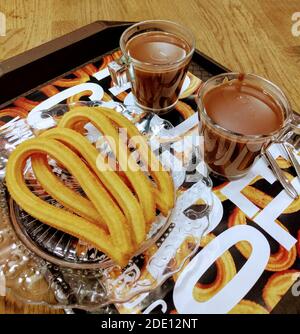 Traditionelle spanische Churros mit heißer Schokolade auf einem Holztisch. Traditionelle spanische süße Backwaren. Stockfoto