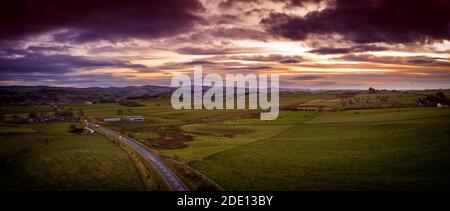 Blick nach Süden auf die A7 in Richtung Hawick eingebettet unter den Hügeln unten, wie die Sonne an einem anderen Novembertag untergeht. Stockfoto