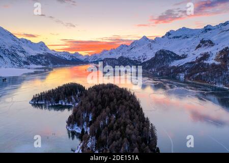 Luftaufnahme von brennendem Himmel bei Sonnenuntergang auf gefrorenem Sils-See und schneebedeckten Bergen, Malojapass, Graubünden Kanton, Schweizer Alpen, Schweiz, Europa Stockfoto