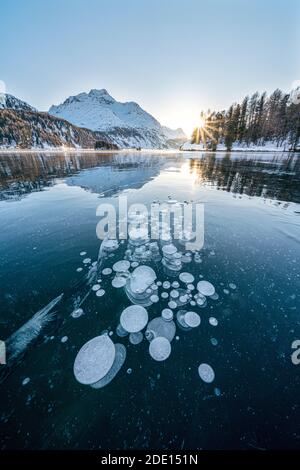 Eisblasen gefangen im gefrorenen Sils See bei Sonnenuntergang mit Piz Da La Margna im Hintergrund, Engadin, Kanton Graubünden, Schweiz, Europa Stockfoto