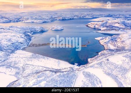 Luftaufnahme der Norwegian County Road 98 entlang schneebedeckter Berge über Laksefjorden, Lebesby, Kunes, Troms Og Finnmark, Arktis, Norwegen Stockfoto