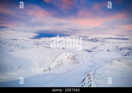 Rosa Himmel bei Sonnenaufgang über Tanafjordveien Straße überqueren die schneebedeckten Berge, Tana, Troms Og Finnmark, Arktis, Nordnorwegen Stockfoto