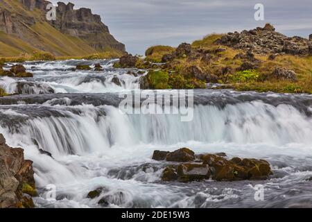 Eine klassische isländische Landschaft, ein Fluss fließt entlang der Basis einer Klippe, der Fossalar River, in der Nähe von Kirkjubaejarklaustur, Island, Polarregionen Stockfoto