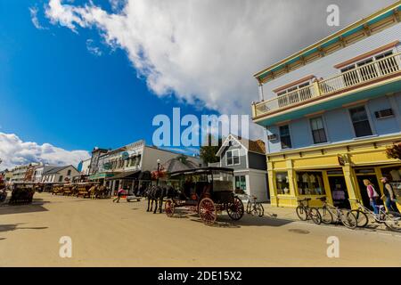 Straßen mit Pferden und Kutschfahrten, die von wunderschönen bunten Gebäuden gesäumt sind, Mackinac Island, Michigan, USA, Nordamerika Stockfoto