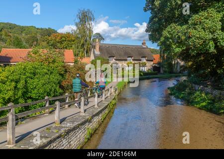 Blick auf Radfahrer, Reetgedeckte Hütte am Flussufer und Thornton Beck, Thornton Dale, North Yorkshire, England, Großbritannien, Europa Stockfoto