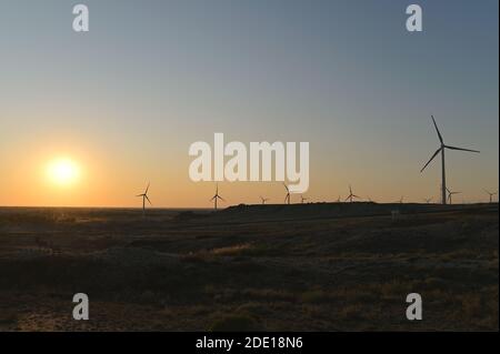 Blick bei Sonnenuntergang auf einen weitläufigen Windpark in der Wüste in der Nähe von Wucaitan, Burqin County, Nord Xinjiang, China Stockfoto