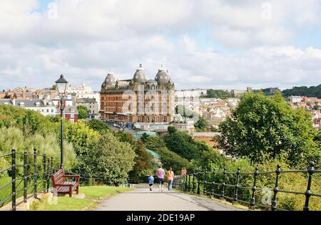 Spaziergang entlang des Pfades an der South Bay in Richtung Scarborough's Grand Hotel an einem Sommertag. Das Hotel ist das prominenteste Gebäude in diesem Resort. Stockfoto