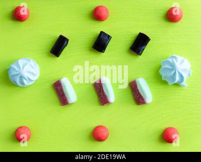 Süßes Muster-Flachlappen für Süßwarenladen, bunte italienische Süßigkeiten: Marmelade, Marshmallow und Lakritz auf grünem Hintergrund. Stockfoto