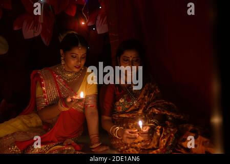 Zwei schöne indische bengalische Frauen in indischen traditionellen Kleid Beleuchtung Diwali Lampen sitzen auf dem Boden am Diwali Abend. Indischer Lebensstil Stockfoto