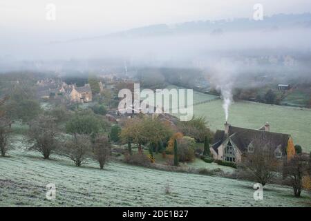 Frostiger nebliger Herbstmorgen bei Sonnenaufgang mit Blick auf Naunton. Cotswolds, Gloucestershire, England Stockfoto