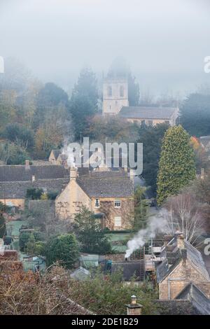 Frostiger nebliger Herbstmorgen bei Sonnenaufgang mit Blick auf Naunton. Cotswolds, Gloucestershire, England Stockfoto